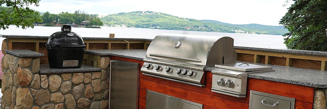 Closeup of outdoor kitchen on granite patio looking out to a New Hampshire lake