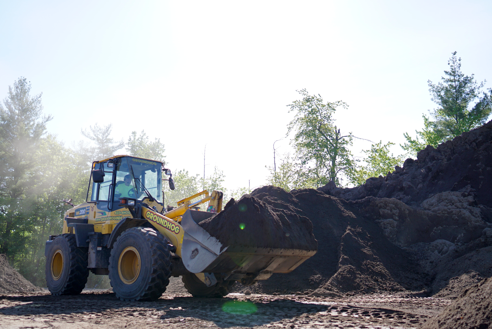 loader carrying topsoil to a truck